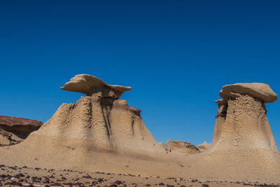 Low angle view of desert against clear blue sky