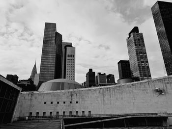 Low angle view of skyscrapers against cloudy sky