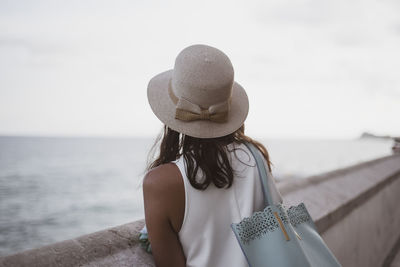 Rear view of woman wearing hat against sea against sky