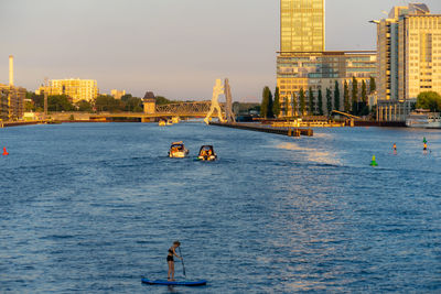 Woman paddleboarding in sea against buildings in city