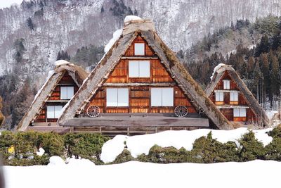 Snow covered house and trees against sky