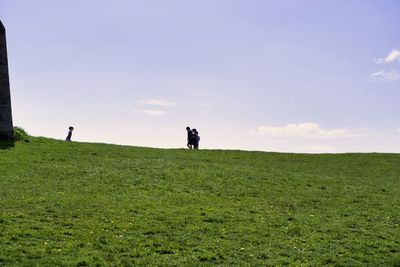 Men standing on field against sky
