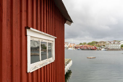Old picturesque red wooden building by sea against sky