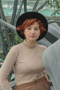 A beautiful plus size girl with red hair among green branches of tropical plants