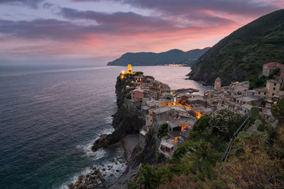 Aerial view of buildings by sea against sky during sunset