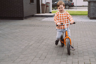 Child playing racing on bike in the home yard. boy riding fast around private house. family games