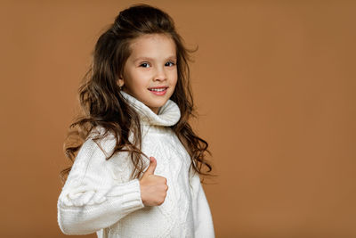 Portrait of young woman standing against yellow background