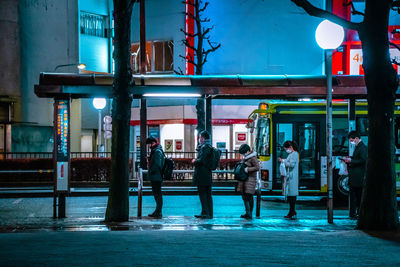 People walking on illuminated street in city