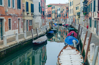 Canal in venice, italy with boats and pedestrian area in a residential part of the city