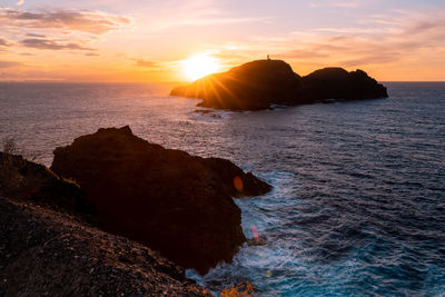 Rocks on sea against sky during sunset