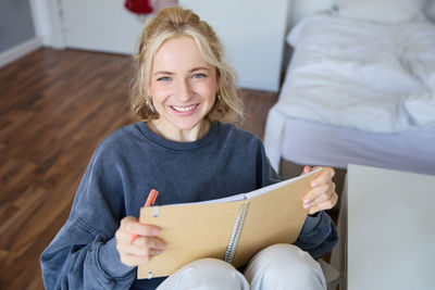 Portrait of young woman reading book at home