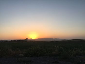 Scenic view of silhouette field against clear sky during sunset