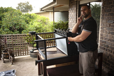 Side view of a man assembling a barbecue in his backyard