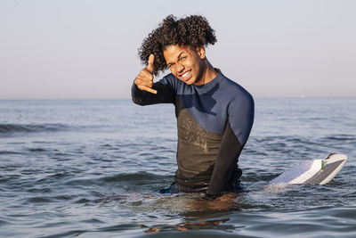 Young woman smiling in sea against sky