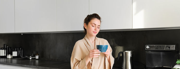 Portrait of young woman standing at home