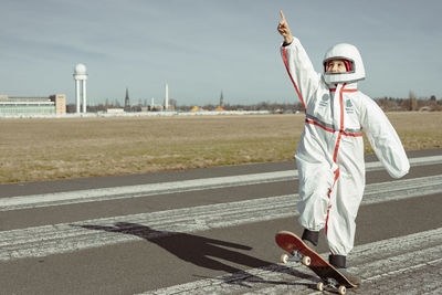 Empowered astronaut girl on a skateboard pointing her hand to the sky, international women's day
