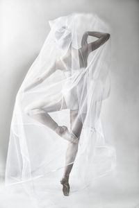 Woman wrapped in textile while dancing against white background