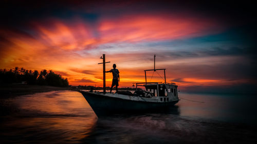Sailboat sailing on sea against dramatic sky during sunset