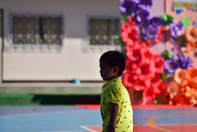 Rear view of boy looking at multi colored standing outdoors