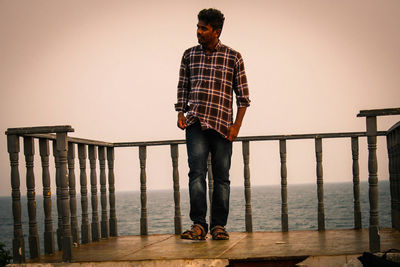 Man standing on observation point over sea against sky