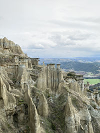 Scenic view of rock formations on landscape against cloudy sky