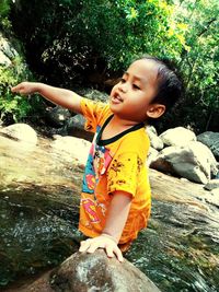 Cute baby girl on rock at shore