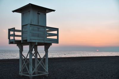 Lifeguard hut on beach against sky during sunset