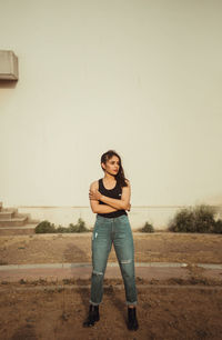 Portrait of smiling young woman standing against wall