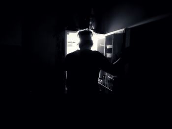 Rear view of silhouette man standing in dark room