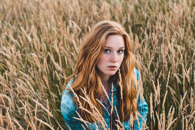 Portrait of woman standing amidst plants on wheat field