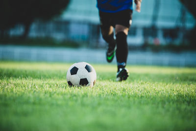 Low section of man playing soccer ball on grass