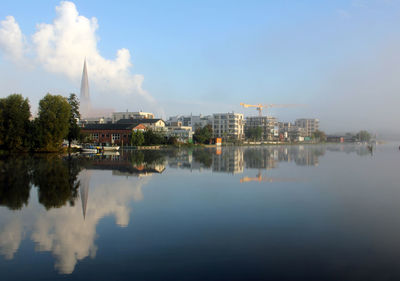 Reflection of buildings on calm lake against sky