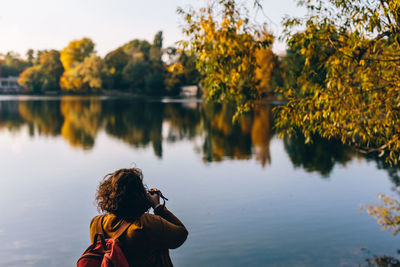 Rear view of woman photographing lake