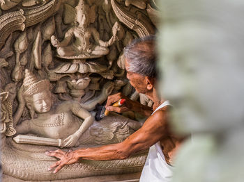 Side view of senior man carving statues