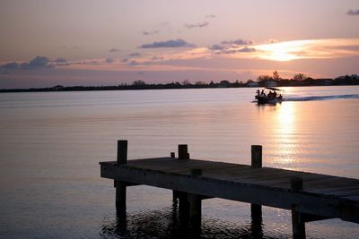 People sailing boat in lake against sky during sunset