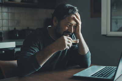 Young man using mobile phone while sitting on table