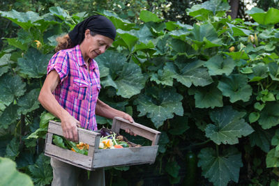 Rural woman with the harvest of vegetables from the organic garden in a wooden crate person