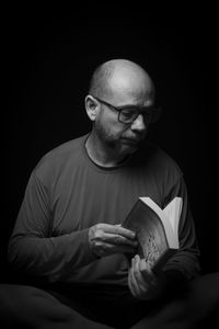 Portrait of man sitting against black background