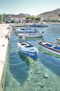 Boats moored on shore by lake against sky