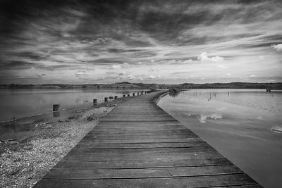 Wooden pier leading towards sea against sky