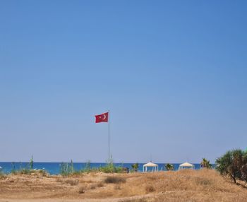 Flag on field against clear blue sky