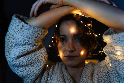 A woman is decorated with a glowing christmas lights holding her hands above her head.