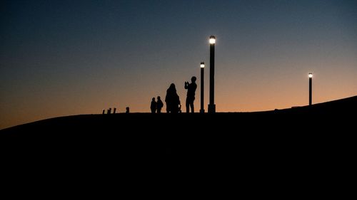 Silhouette people against clear sky at sunset