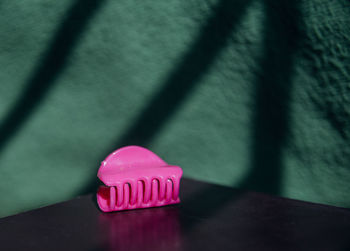 A pink object behind a green wall