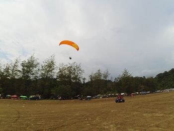 People paragliding on field against sky