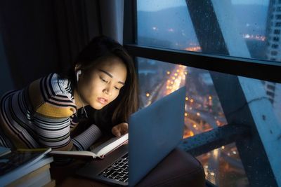 Woman looking away while sitting on window