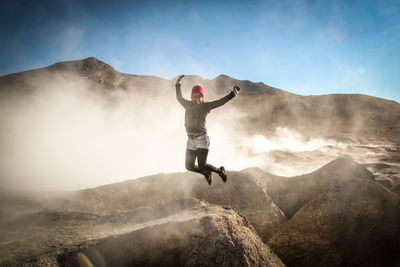 Full length of man jumping on mountain against sky