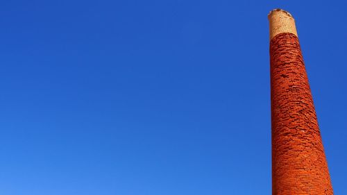 Low angle view of smoke stack against clear blue sky