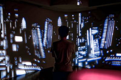 Rear view of woman standing in illuminated room