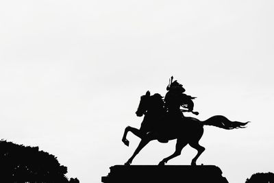 Low angle view of silhouette statue against clear sky